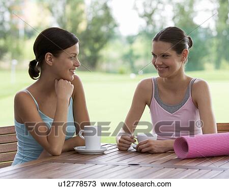 Two young women drinking coffee after a yoga class View Large Photo Image Stock Image - Two young women drinking coffee after a yoga class. Fotosearch
