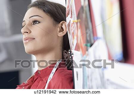 Stock Image - Close-up of a fashion designer beside a mood board and thinking. Fotosearch