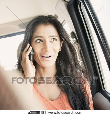 Stock Image - Close-up of a young woman talking on a mobile phone and traveling in a car. Fotosearch