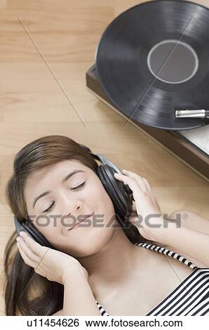 Stock Photograph - Close-up of a young woman wearing headphones and listening to music. Fotosearch