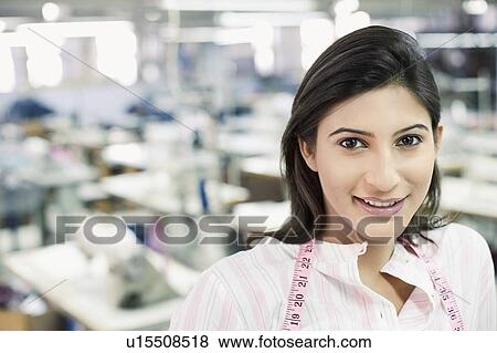Stock Photo - Portrait of a female fashion designer smiling with a tape measure around her neck. Fotosearch