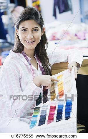 Stock Photography - Portrait of a female fashion designer holding a book of fabric swatches. Fotosearch