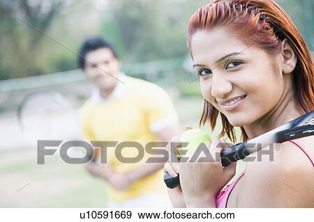 Portrait of a young woman holding a tennis racket and smiling View Large Photo Image Stock Photo - Portrait of a young woman holding a tennis racket and smiling. Fotosearch