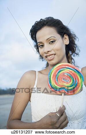 Stock Photo - Portrait of a young woman holding a candy and smiling. Fotosearch