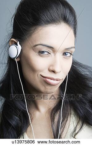 Portrait of a young woman listening to headphones and smirking View Large Photo Image Stock Photograph - Portrait of a young woman listening to headphones and smirking. Fotosearch
