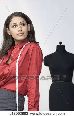 Stock Image - Side profile of a female designer with a measuring tape around her neck. Fotosearch