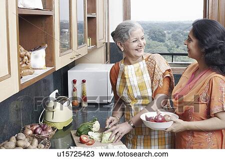 Stock Image - Two women talking in the kitchen. Fotosearch