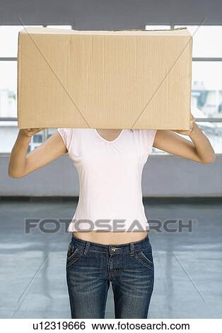 Stock Photograph - Young woman holding a cardboard box in front of her face. Fotosearch