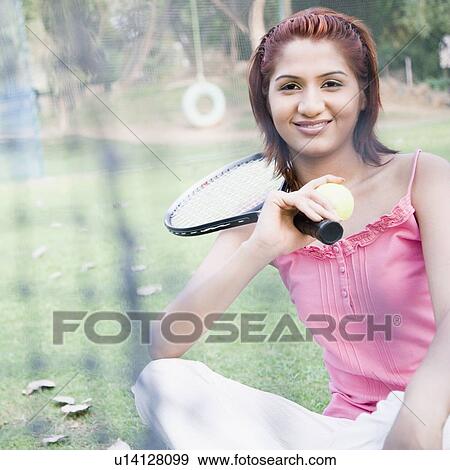 Stock Photo - Young woman holding a tennis ball and a tennis racket. Fotosearch