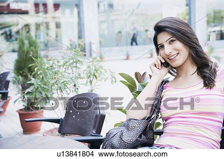 Young woman talking on a mobile phone and smiling View Large Photo Image Picture - Young woman talking on a mobile phone and smiling. Fotosearch
