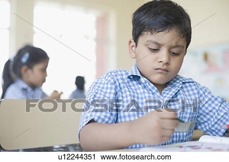 Stock Image - Close-up of a schoolboy coloring his drawing on a notepad. Fotosearch