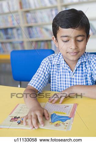 Close-up of a schoolboy reading a book in a library View Large Photo Image Stock Photo - Close-up of a schoolboy reading a book in a library. Fotosearch