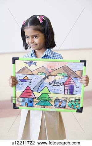 Stock Image - Close-up of a schoolgirl holding a painting and smiling. Fotosearch