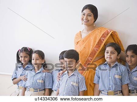 Female teacher and students standing by a whiteboard and smiling View Large Photo Image Stock Photograph - Female teacher and students standing by a whiteboard and smiling. Fotosearch