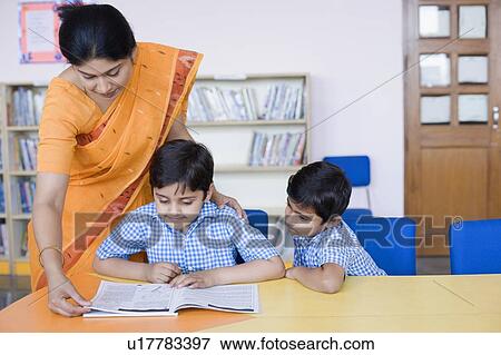 Female teacher teaching her students in a library View Large Photo Image Stock Photo - Female teacher teaching her students in a library. Fotosearch