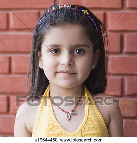 Stock Photo - Portrait of a girl standing in front of a wall. Fotosearch