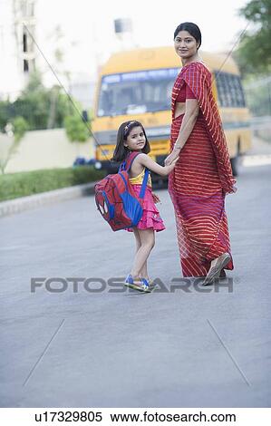 Portrait of a mid adult woman holding hand of her daughter and walking on the road View Large Photo Image Stock Photography - Portrait of a mid adult woman holding hand of her daughter and walking on the road. Fotosearch