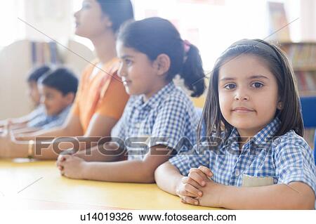 Stock Photograph - Portrait of a school girl with her classmates and a teacher sitting at a table. Fotosearch