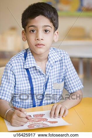 Stock Photo - Portrait of a schoolboy drawing on a sheet of paper. Fotosearch