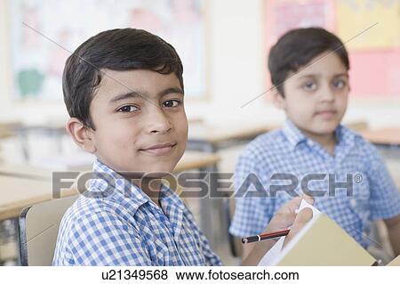 Portrait of a schoolboy writing in a notepad with a pencil View Large Photo Image Stock Photo - Portrait of a schoolboy writing in a notepad with a pencil. Fotosearch