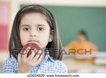 Stock Photo - Portrait of a schoolgirl holding an apple. Fotosearch
