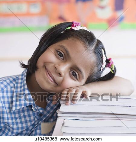 Portrait of a schoolgirl leaning on a stack of books and smirking View Large Photo Image Stock Photo - Portrait of a schoolgirl leaning on a stack of books and smirking. Fotosearch