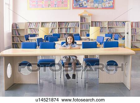 Portrait of a schoolgirl sitting at a desk in a library View Large Photo Image Picture - Portrait of a schoolgirl sitting at a desk in a library. Fotosearch