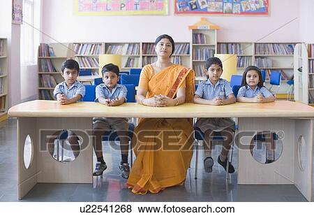 Portrait of a teacher and students sitting at a table View Large Photo Image Stock Photo - Portrait of a teacher and students sitting at a table. Fotosearch