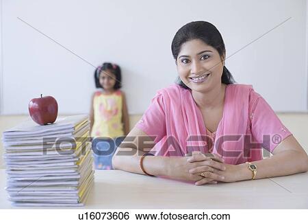 Portrait of a teacher smiling with a schoolgirl standing in the background View Large Photo Image Stock Photograph - Portrait of a teacher smiling with a schoolgirl standing in the background. Fotosearch