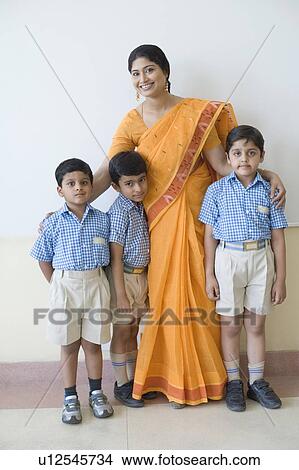 Picture - Portrait of a teacher standing with three schoolboys and smiling. Fotosearch