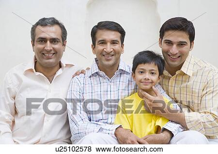 Stock Photo - Portrait of a young man and two mid adult men smiling with a boy. Fotosearch
