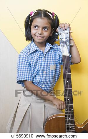 Schoolgirl holding a guitar and smirking in a music class View Large Photo Image Stock Image - Schoolgirl holding a guitar and smirking in a music class. Fotosearch