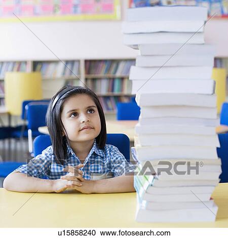 Schoolgirl looking at a stack of books View Large Photo Image Stock Image - Schoolgirl looking at a stack of books. Fotosearch