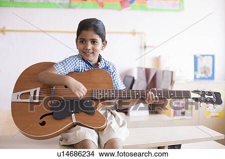 Schoolgirl sitting on a bench and playing a guitar View Large Photo Image Picture - Schoolgirl sitting on a bench and playing a guitar. Fotosearch