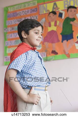 Stock Image - Side profile of a boy imitating to be a superhero. Fotosearch