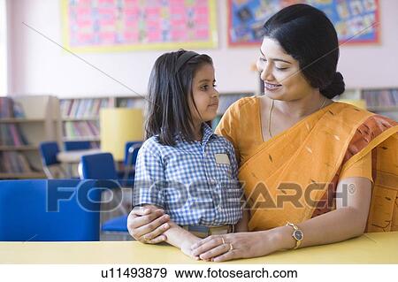 Teacher sitting in a library with her student and smiling View Large Photo Image Stock Photo - Teacher sitting in a library with her student and smiling. Fotosearch
