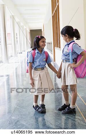 Two girls standing in a corridor with holding hands of each other View Large Photo Image Stock Photography - Two girls standing in a corridor with holding hands of each other. Fotosearch