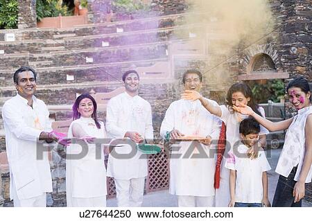 Stock Image - Two mid adult couples and a young couple with a boy celebrating holi. Fotosearch