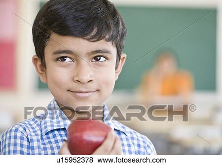 Stock Photo - Close-up of a schoolboy holding an apple and smiling. Fotosearch