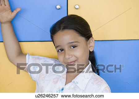 Stock Photo - Portrait of a girl smiling with her hand raised. Fotosearch
