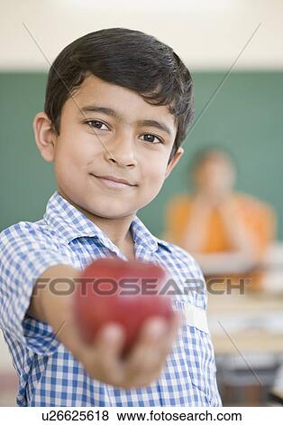 Stock Photo - Portrait of a schoolboy holding an apple and smiling. Fotosearch