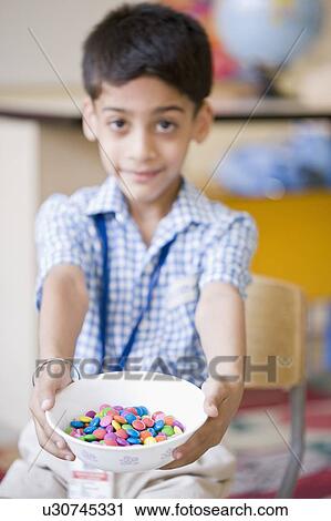 Portrait of a schoolboy holding candies in a bowl View Large Photo Image Stock Image - Portrait of a schoolboy holding candies in a bowl. Fotosearch