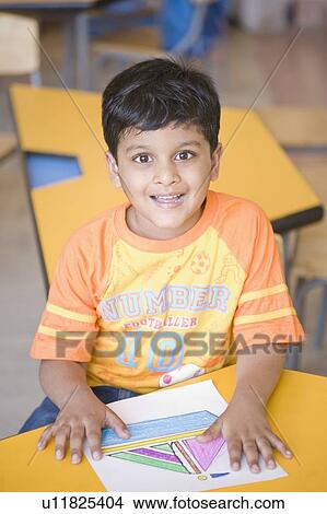 Picture - Portrait of a schoolboy sitting in a classroom and smiling. Fotosearch