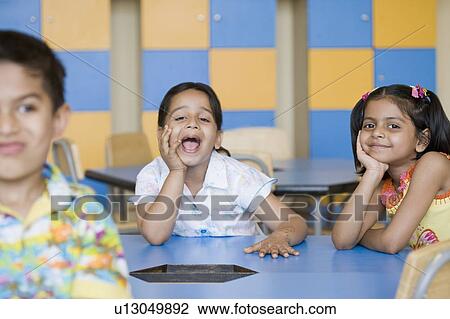 Portrait of a schoolgirl sitting with her friends in a class room and shouting View Large Photo Image Stock Image - Portrait of a schoolgirl sitting with her friends in a class room and shouting. Fotosearch