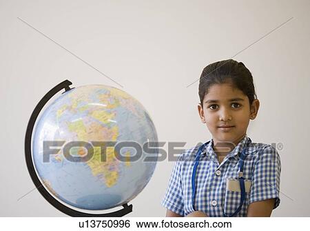 Stock Photograph - Portrait of a schoolgirl standing near a globe. Fotosearch