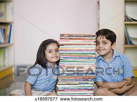 Stock Photo - School boy and a schoolgirl sitting on the floor with a stack of books. Fotosearch