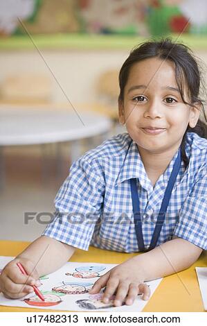 Schoolgirl sitting at a table and drawing with crayons View Large Photo Image Stock Image - Schoolgirl sitting at a table and drawing with crayons. Fotosearch