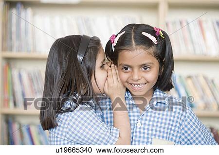 Side profile of a schoolgirl whispering into her friend's ear View Large Photo Image Stock Image - Side profile of a schoolgirl whispering into her friend's ear. Fotosearch