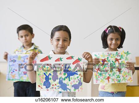 Two schoolboys with a schoolgirl holding their paintings View Large Photo Image Stock Photo - Two schoolboys with a schoolgirl holding their paintings. Fotosearch