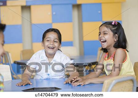 Two schoolgirls with a schoolboy laughing in a classroom View Large Photo Image Stock Photo - Two schoolgirls with a schoolboy laughing in a classroom. Fotosearch